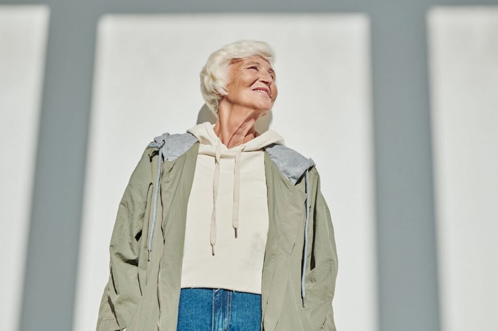 Senior woman wearing stylish outfit smiles while enjoying the sunny day.